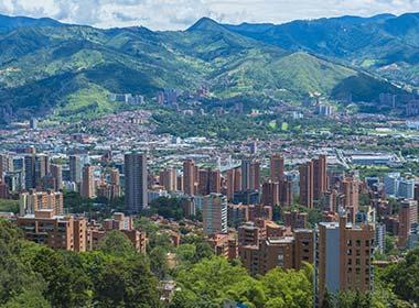 city of medellin colombia with high rise buildings and city surrounded by green hills and mountains