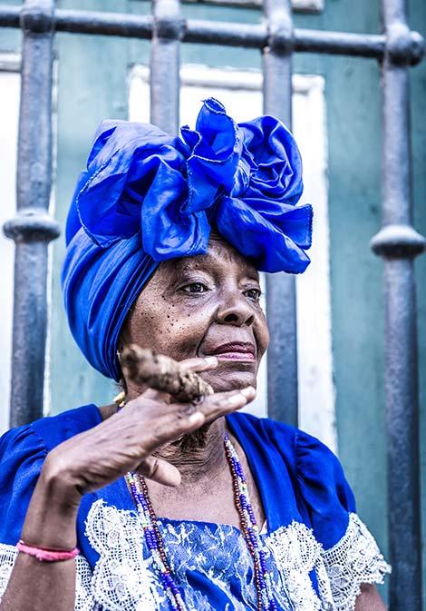 cuban woman wearing blue with blue headscarf smoking a cuban cigar