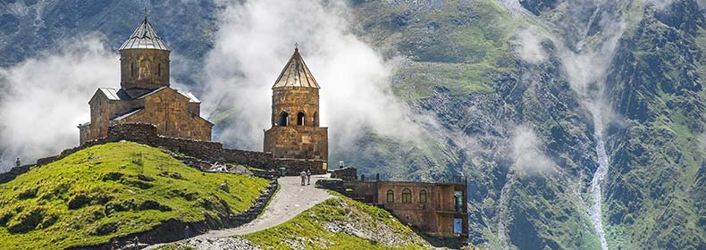 famous Gergeti Trinity Church in Stepantsminda georgia on a hill mountains in the background