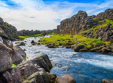 stream with grass and rocks on a sunny day in iceland