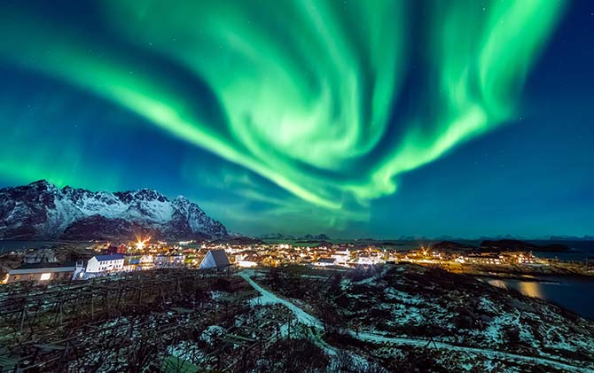 green northern lights or aurora borealis in iceland over a lake and glaciers