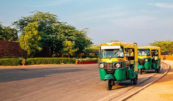 a line of tuk tuks rickshaws waiting for people to travel by rickshaw in india