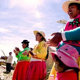 holiday tourists visit as local natives sings and dance on the reed islands on lake titicaca near puno, peru