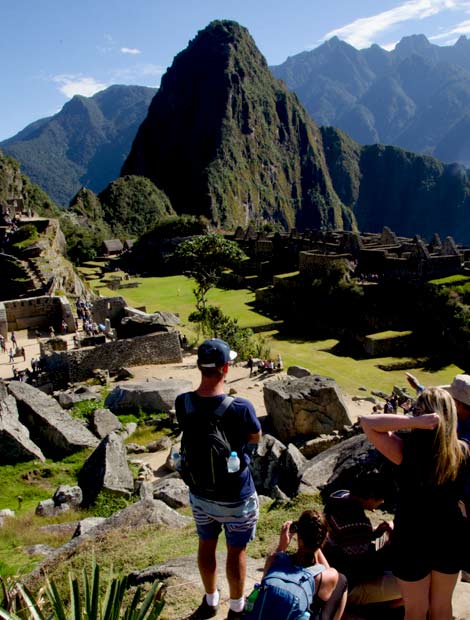 Couple of adventure travellers look in awe of their surroundings as they sit overlooking acient Machu Picchu ruins