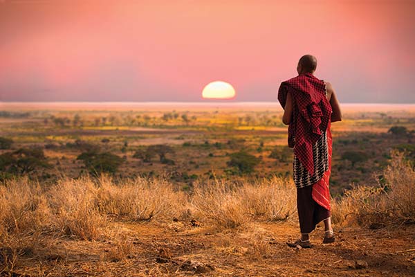 tanzanian man looking at the sunset over african landscape in tanzania