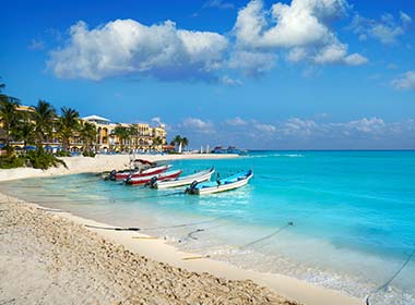 boats in the blue sea beach with palmtrees at playa del carmen mexico