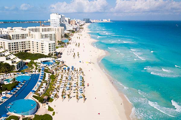 sunloungers and pools along the white stretch of sand on cancun beach in mexico